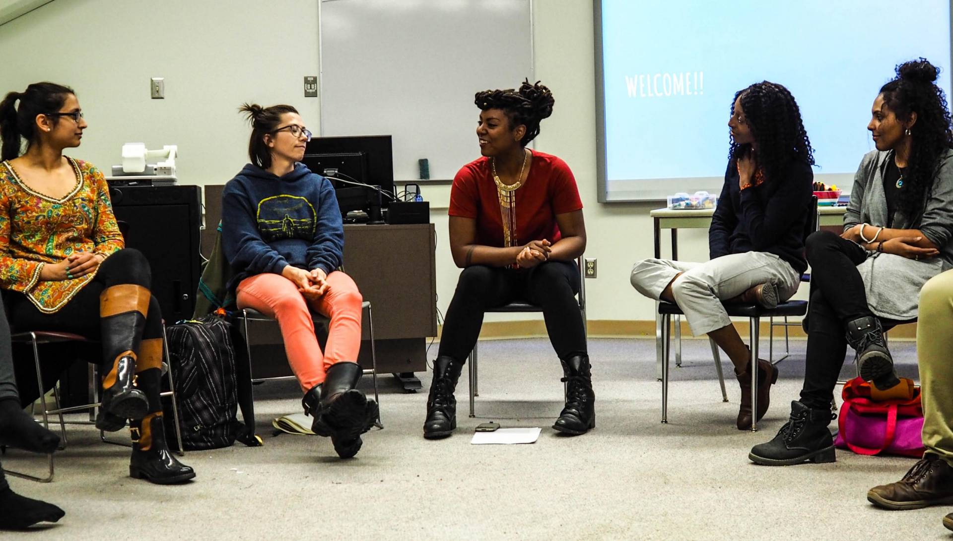 Image of Ruby and several youth sitting on chairs in a circle engaged in conversation
